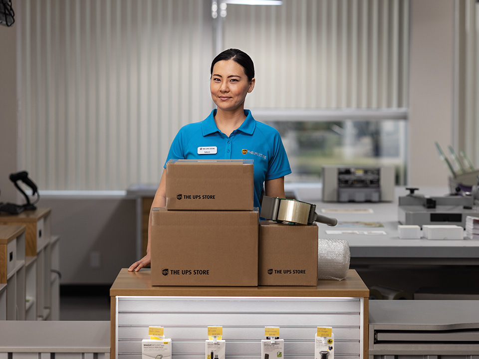 The UPS Store associate standing behind a pile of boxes